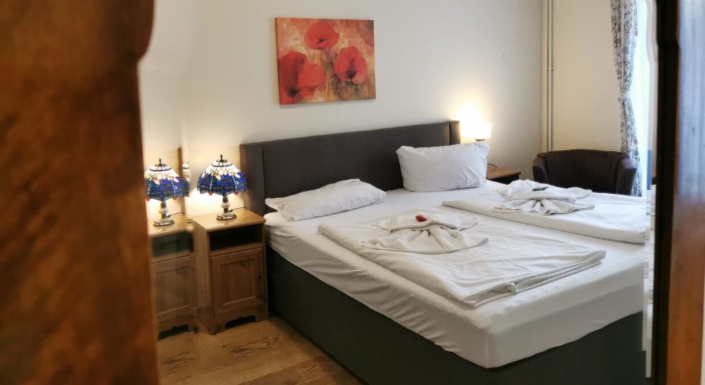 Zimmerfoto mit Bett und Nachttisch aus der Pension Tempelhof.