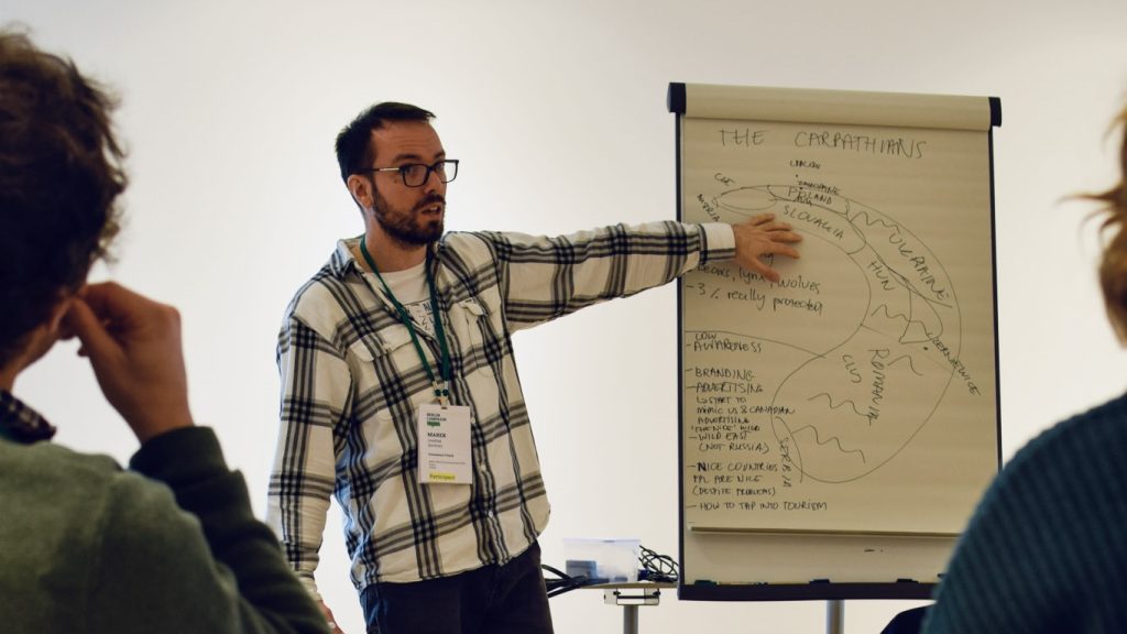 Photograph of a man giving a workshop and using a flipchart.